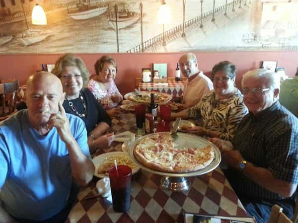 a group of happy customers smiling with their pizza pie