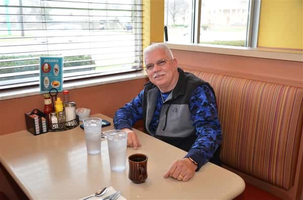 customer sitting down at a booth smiling at the camera