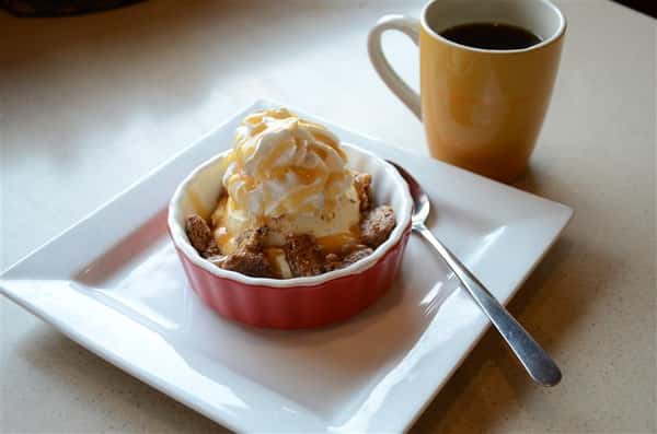ice cream in a bowl with whipped cream and walnuts with a cup of coffee