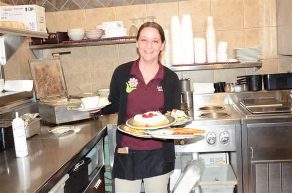 waitress smiling for the camera holding various entrees