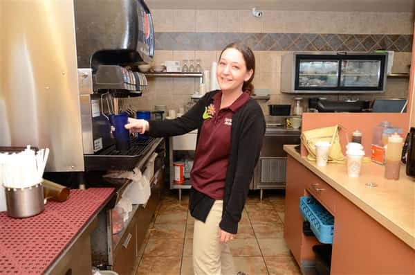 waitress smiling for the camera pouring soda into a cup