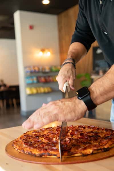 chef cutting a pepperoni pizza