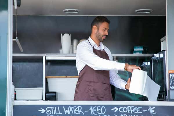 A Pierce Creek employee in an apron is seen taking a paper towel from a roll in the food truck.