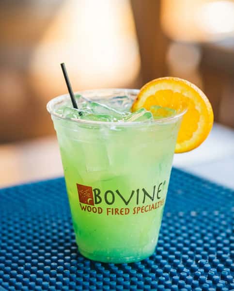 Refreshing green cocktail garnished with an orange slice, served at Bovine's in Murrells Inlet, SC—a waterfront restaurant known for wood-fired specialties and coastal-inspired drinks.