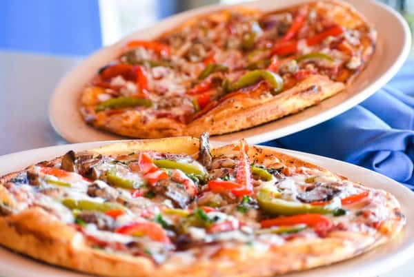 Wood-fired vegetable pizza topped with bell peppers, mushrooms, and melted cheese at Bovine's in Murrells Inlet, SC, highlighting bold coastal flavors and artisanal preparation.
