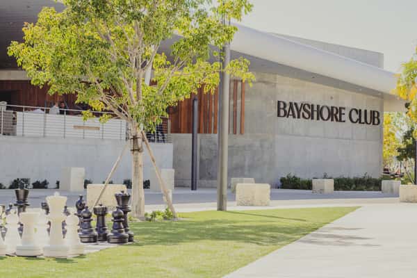 Bayshore Club exterior with modern architecture, landscaped grounds, and a giant outdoor chess set.