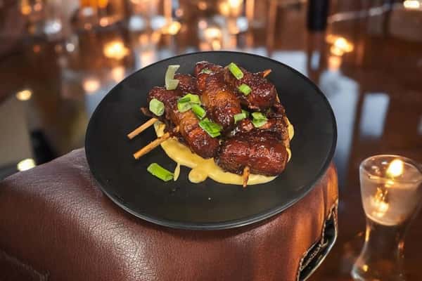 Grilled meat on skewers in a cheesy sauce