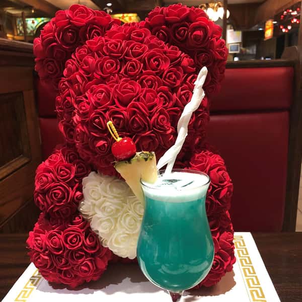 blue Hawaiian in a glass with a pineapple garnish in front of a rose teddy bear