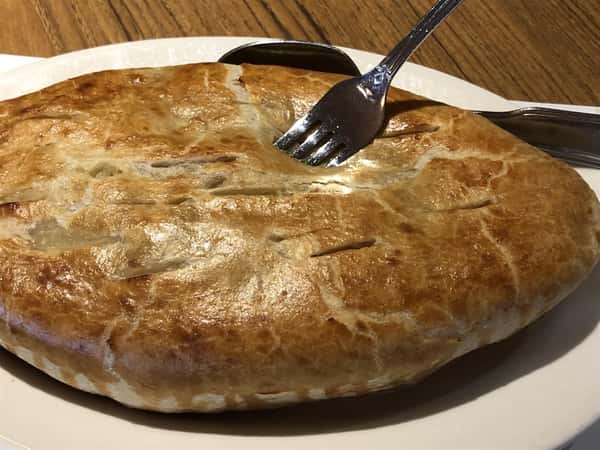 Chicken Pot pie with a fork in it next to Coach House Diner menu
