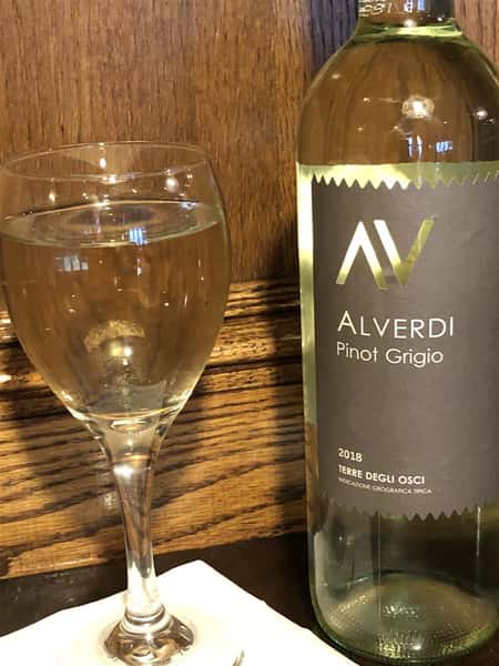 a glass and bottle of white wine on the table
