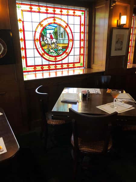 Two cocktails on wooden table in front of stained glass window