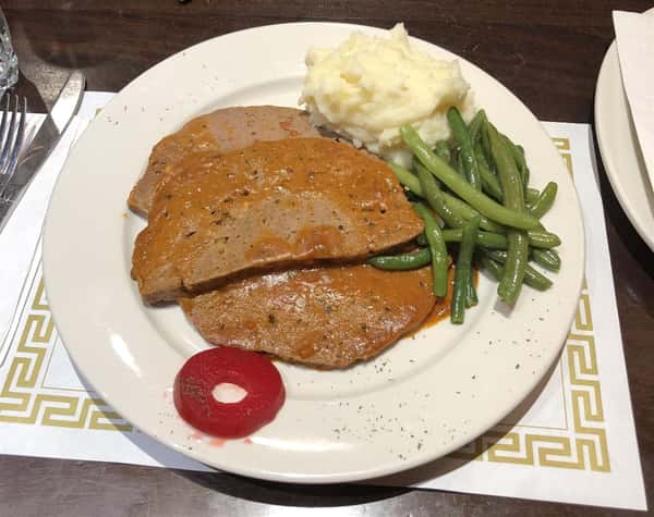 meatloaf on a plate with string beans and mashed potatoes