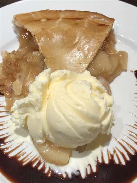 a slice of apple pie, with a scoop of vanilla ice cream beside it