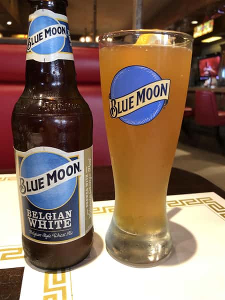 Blue Moon Beer in a bottle and a cup next to each other