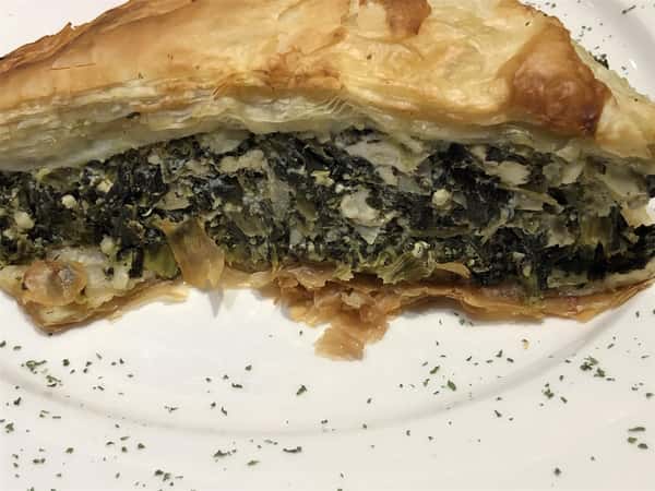 a piece of spinach pie with a flaky crust