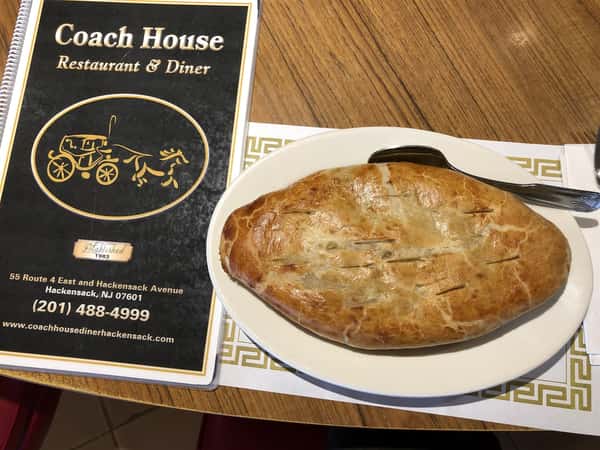 Chicken Pot pie with a fork in it next to Coach House Diner menu