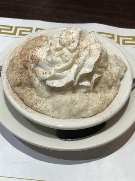 rice pudding in a bowl with whipped cream and cinnamon on top
