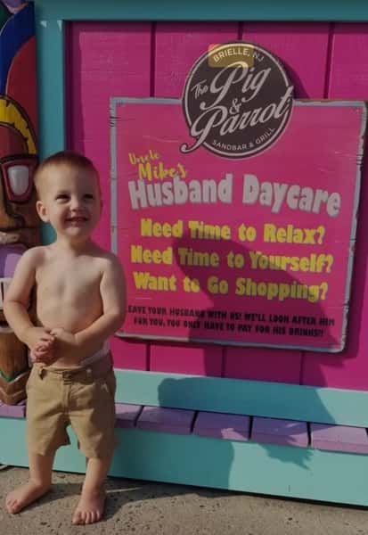 Young guest in front of husband daycare sign