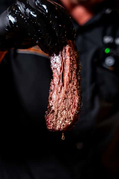 Pitmaster holding up a slice of juicy smoked brisket