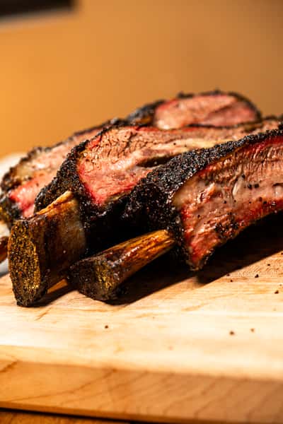 Large beef ribs on a wooden cutting board