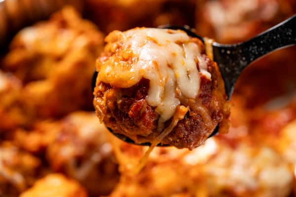 A closeup of a meatball with mozzarella cheese