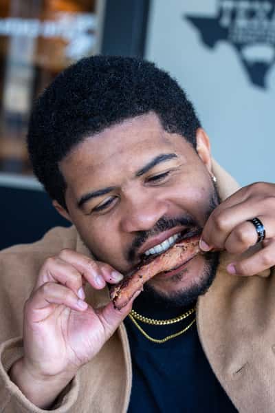 Male customer biting into a pork bbq rib