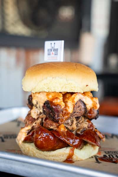 Stacked bbq sandwich with pulled pork, brisket, smoked sausage and pimento cheese
