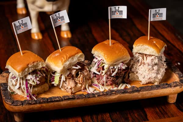 Four pulled pork sliders on a wooden serving tray