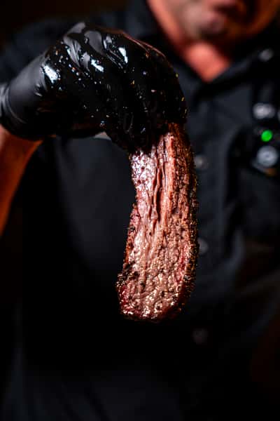 Hand holding a freshly sliced piece of beef brisket