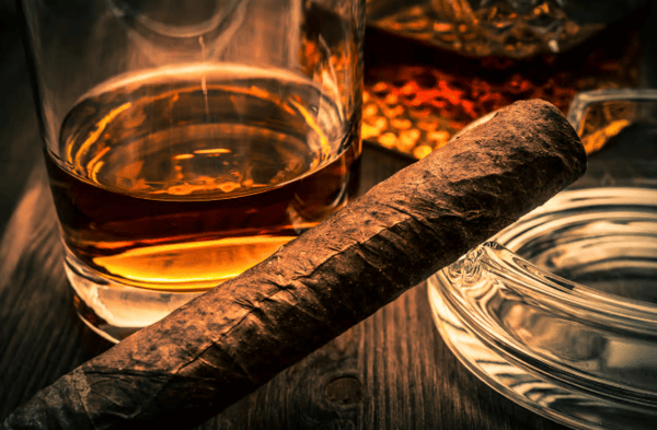 cigar across a place setting.  bucket glass on table and silver disk.  