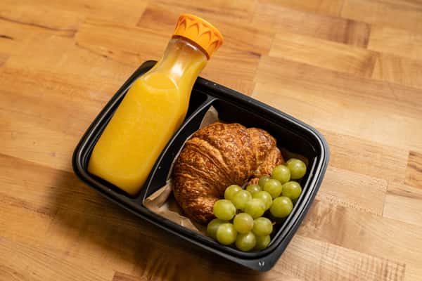 Breakfast box with croissant, green grapes, and orange juice