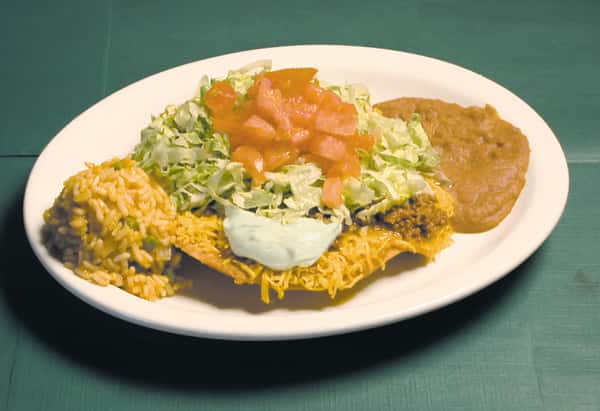 Crispy beef tostada with tomatoes, lettuce and sour cream and a side of rice and beans