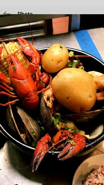 a bowl with lobsters, potatoes, corn and clams
