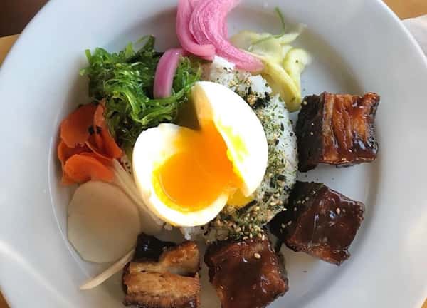 hardboiled egg over rice with side of meat and vegetables