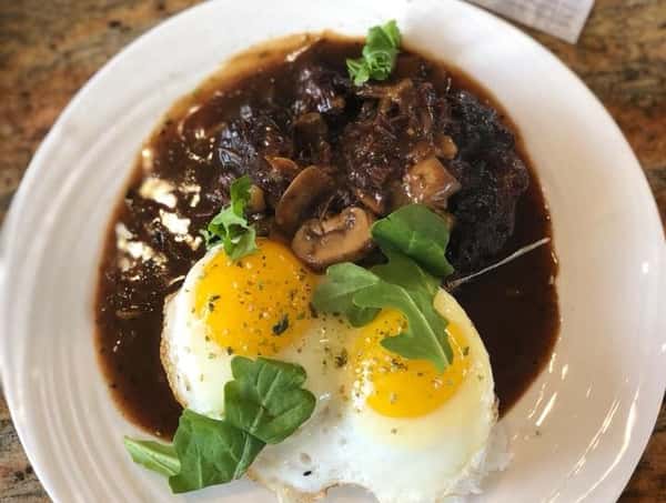 meat served in a brown sauce with mushrooms and egg side