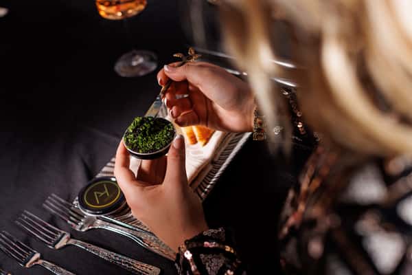 A woman scooping outa sample of food from a small dish.