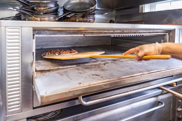 chef putting pizza into oven