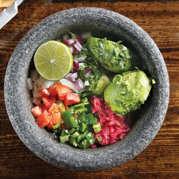 bowl with avocado, onion, tomato, peppers, cabbage and lime.