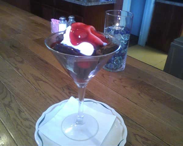 martini glass filled with chocolate dessert with strawberries and whipped cream