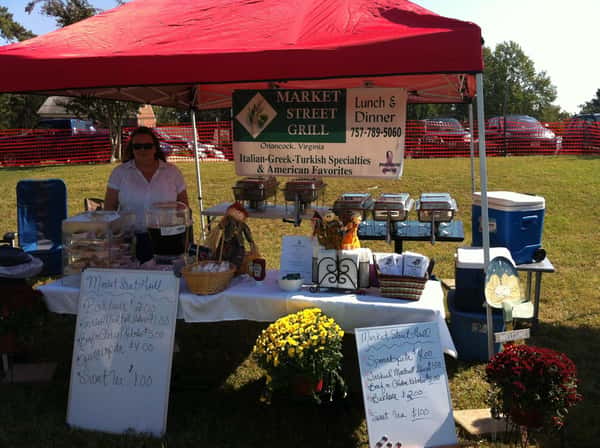outdoor farmers market stand selling food under a tent