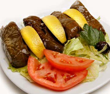Grape leaves with lemon wedges and a side of tomatoes