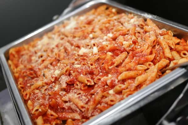 baked ziti in a metal tin covered with cheese