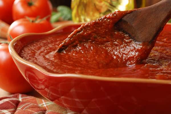 Wooden spoon in a bowl of tomato sauce