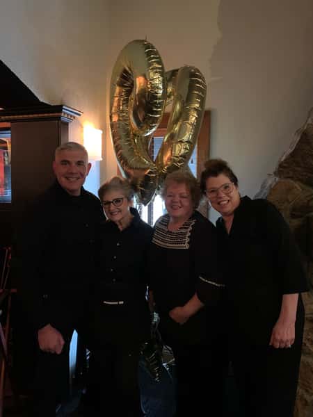 family posing with balloontwo staff membs