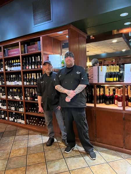 two staff members in front of wine display