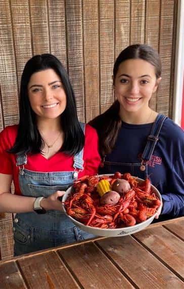 two people holding a plate of boiled crawfish