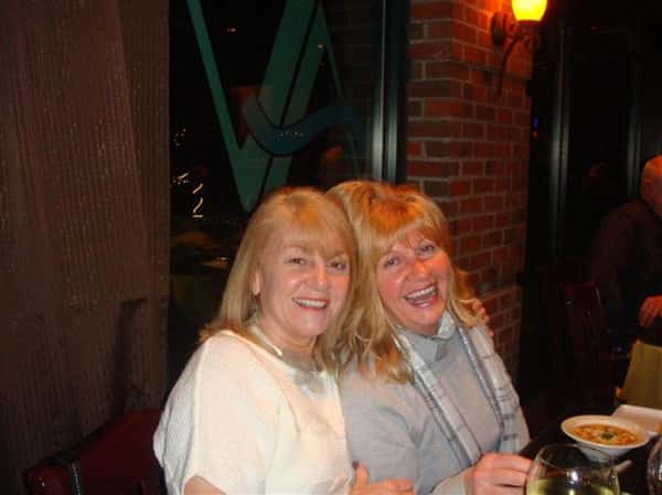 two woman enjoying themselves at the restaurant laughing at the camera