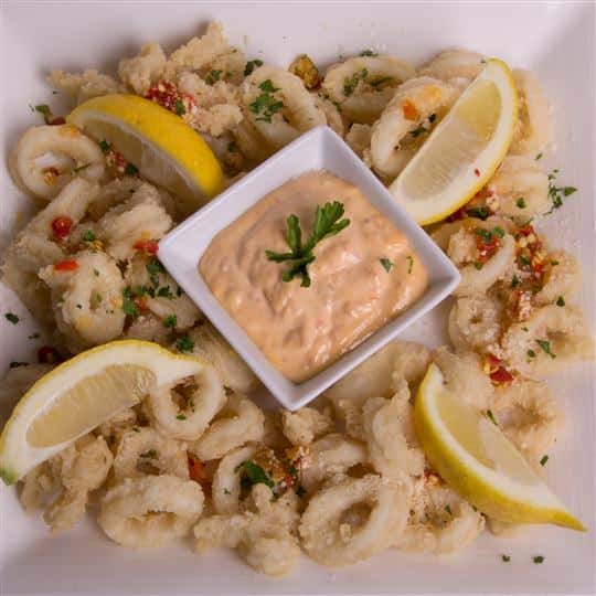 fried calamari with dipping sauce and lemon wedges