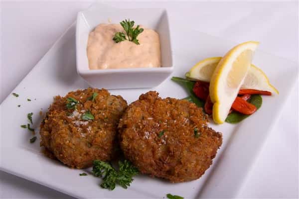 two crab cakes with dipping sauce