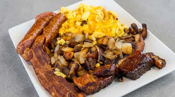A large breakfast platter with scrambled eggs and melted cheese, crispy bacon, potatoes, and glazed onion pieces.